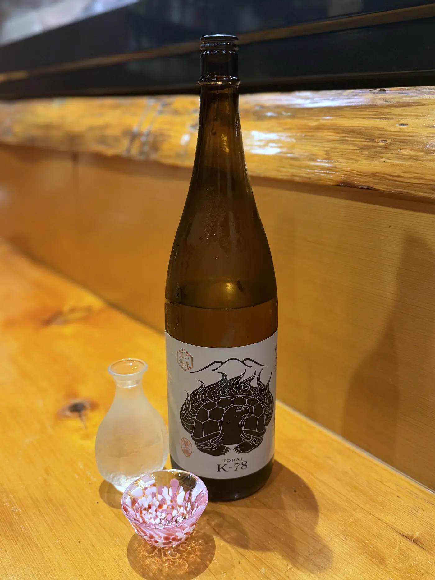 黒いラベルの日本酒の一升瓶と花柄の盃
