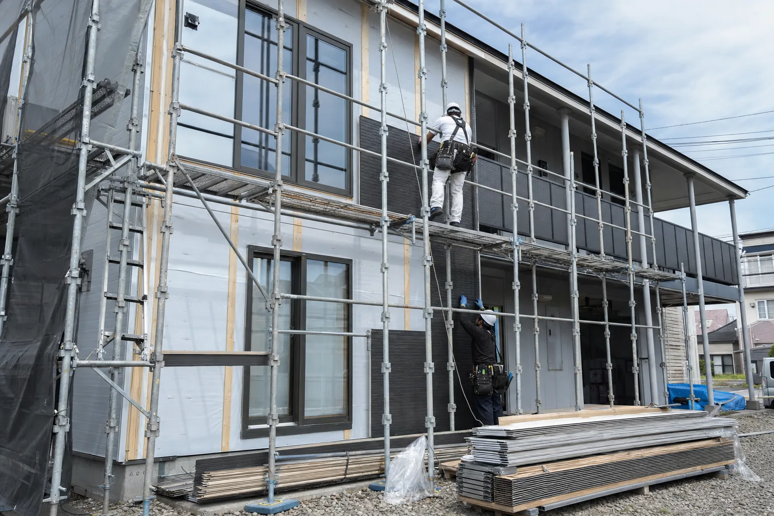 足場を組んだ集合住宅で外壁工事を行うイメージ